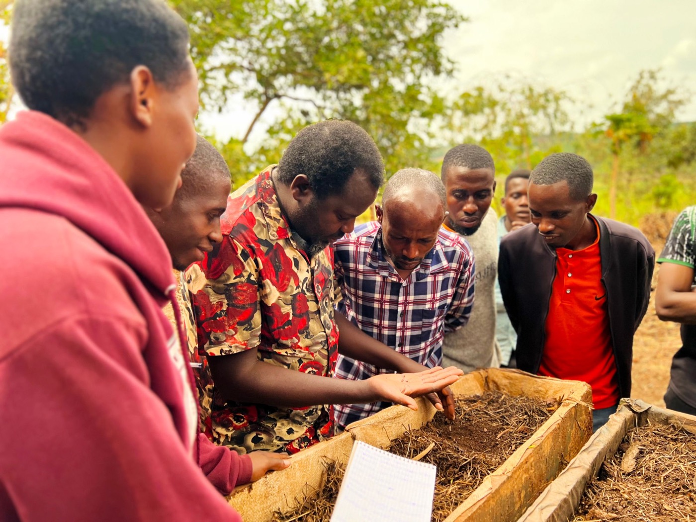 Un formateur montre du compost à un groupe de jeunes agriculteurs